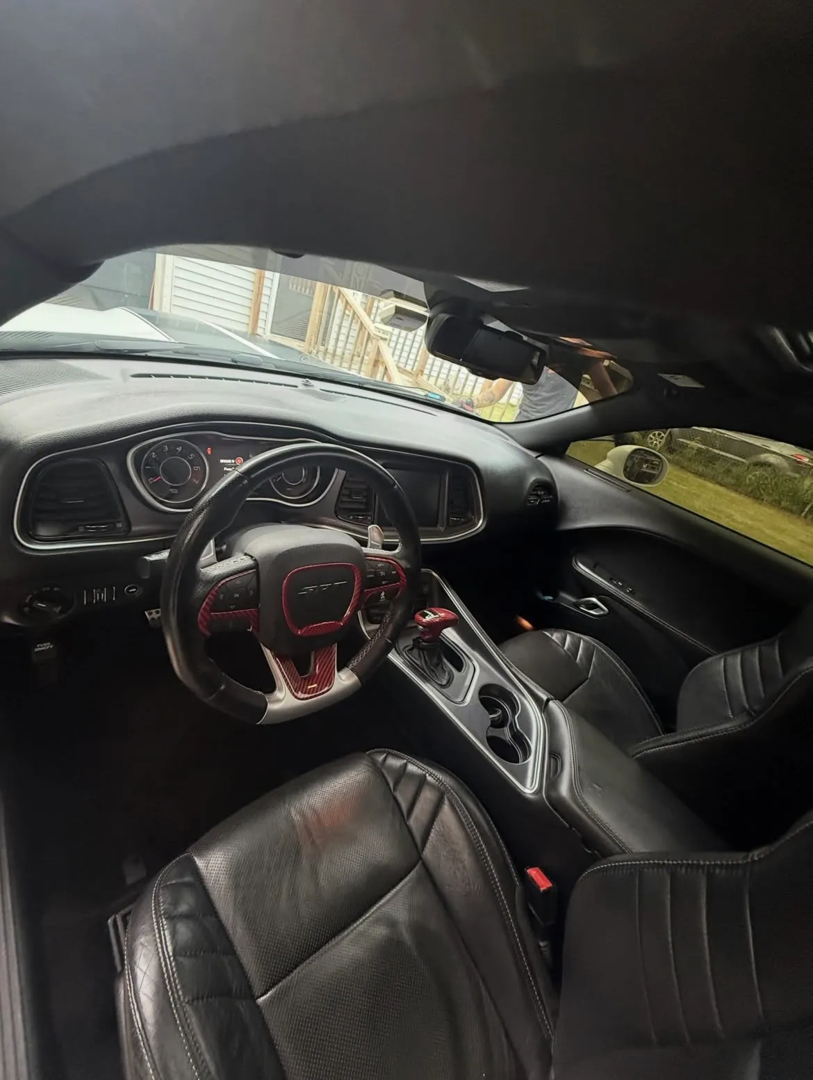 Dodge Challenger SRT interior after detailing, showing the red-accented steering wheel, console and black leather seats.